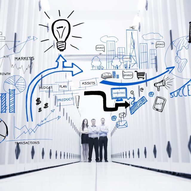 Colleagues standing in a data center in front of drawings